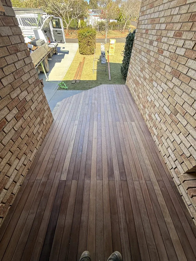Hardwood deck between the house and a brick wall
